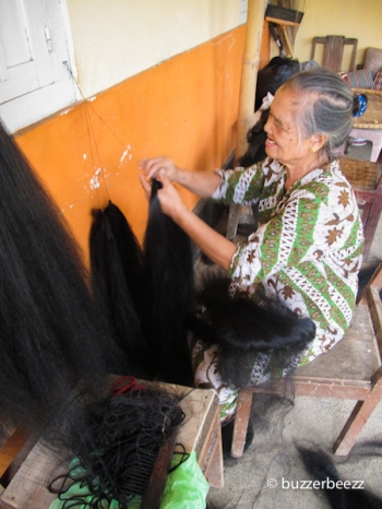 Seorang nenek sibuk menyatukan rambut sintesis helai demi helai